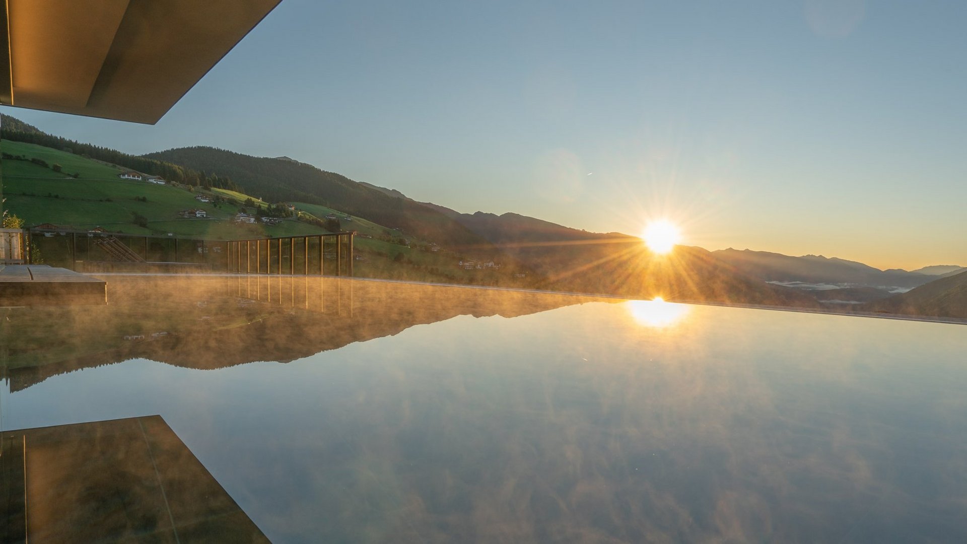 Infinitypool im Hotel Purvita in Meransen bei Sonnenaufgang mit Panoramablick auf das Pustertal, die Dolomiten und die umliegende Berglandschaft Südtirols – ideal für Wellnessurlaub, Entspannung und Luxusurlaub in den Bergen